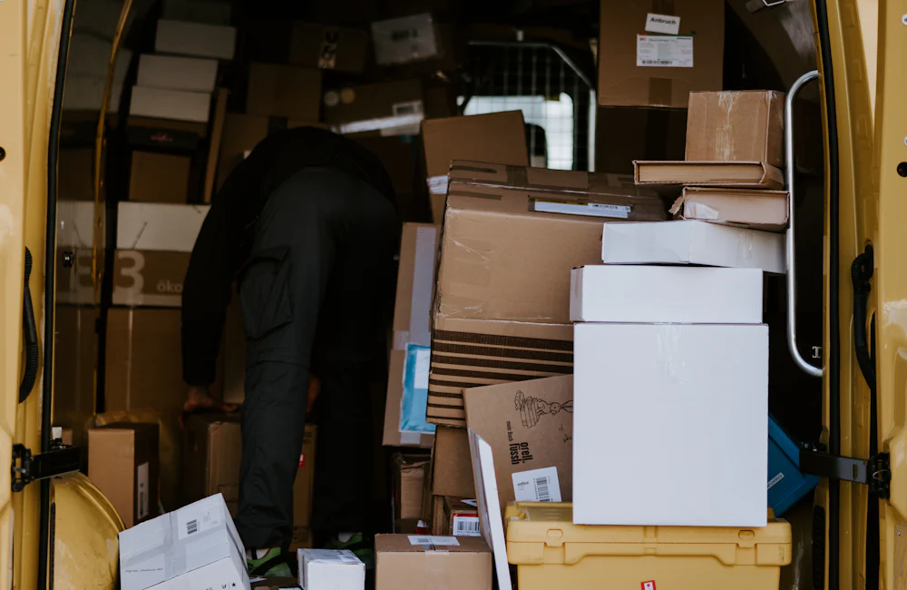 Persona descargando cajas desde la parte trasera de una furgoneta