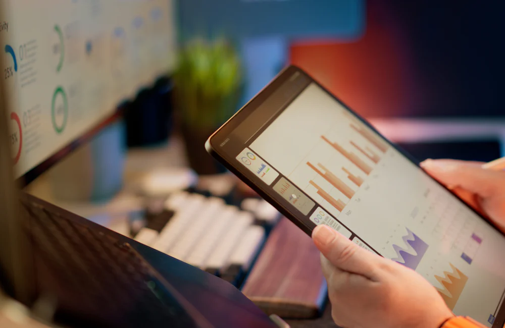 Mano sosteniendo una tableta con gráficos de barras en pantalla